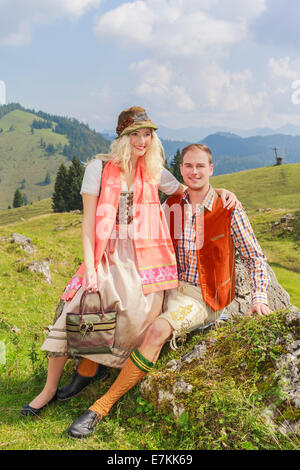 Lovers pants in fashionable traditional Bavarian Dirndl and leather with hat Stock Photo