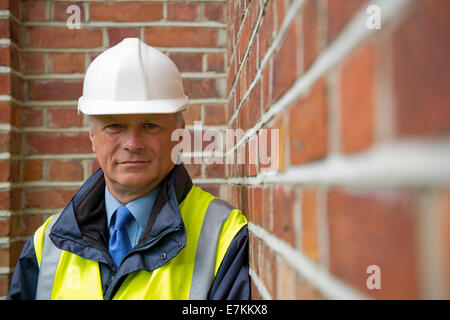 Head and shoulders view of a maintenance engineer against a brick wall background. Stock Photo