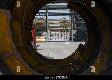 Looking down a used trommel sorting screen as a mine worker walks away in the distance. Stock Photo