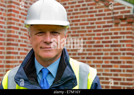 Head and shoulders view of a maintenance engineer against a brick wall background. Stock Photo