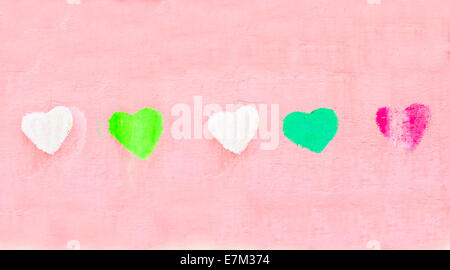 Row of colorful painted heart shapes on a pick wall Stock Photo