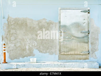 A metal door in a weathered stone wall Stock Photo