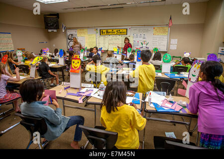 Following a writing assignment of "Our Monster Series," multiracial elementary school students in Irvine, CA, create humorous monster masks as essay themes. Stock Photo