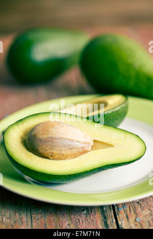 the halved avocados on old wooden table Stock Photo