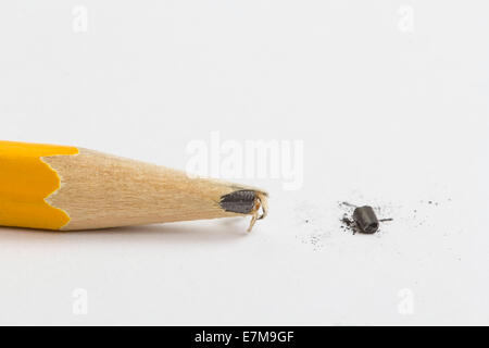 Yellow pencil over a blank sheet of paper with a broken tip. Focus on the tip of the pencil. Stock Photo