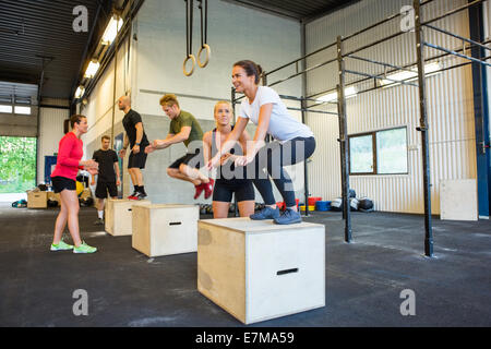Athletes Doing Box Jumps At Gym Stock Photo
