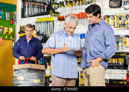 Customers Writing On Checklist In Hardware Store Stock Photo