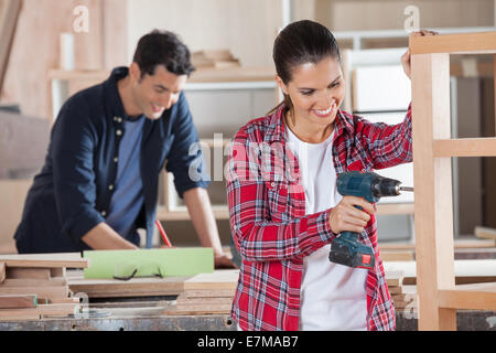 Happy Carpenter Drilling Wood In Workshop Stock Photo