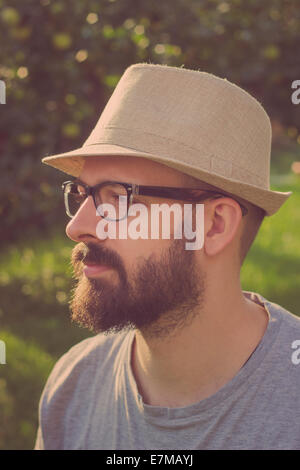 Portrait of a bearded young hipster man daydreaming, looking away. Retro tones