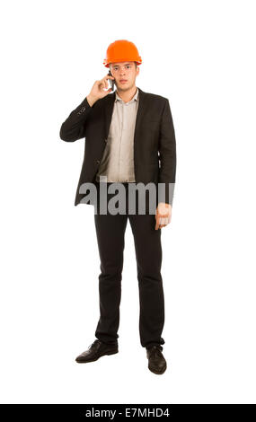 Young Male Engineer in Black Attire and Orange Helmet Talking Client Through Mobile Phone. Isolated on White Background. Stock Photo