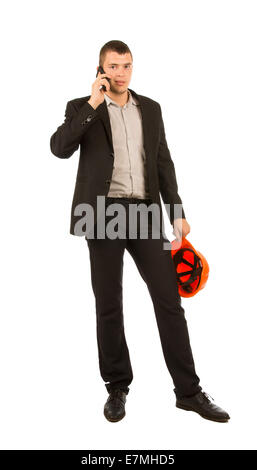 Young Caucasian Male Engineer Calling Through Mobile Phone while Holding Orange Helmet. Isolated on White Background. Stock Photo