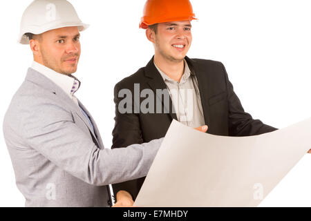 Two architects in hardhats and suits standing discussing a blueprint or building plan that one of them is holding open in his hands, on white. Stock Photo