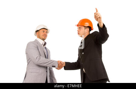 Two Young Angry Male Engineers in Gray and Black Coats Shaking Hands on White Background. Stock Photo