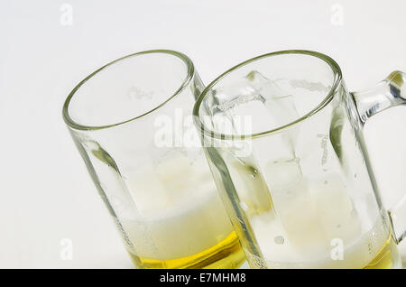 two beer mugs with beer and foam, half full, half empty, on white background, diagonal Stock Photo