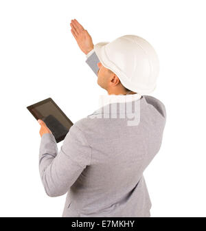Architect or engineer giving instructions standing with his back to the camera holding a tablet with a blank screen and raising his hand, isolated on white. Stock Photo