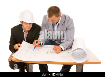 Team of architects working on a plan seated side by side at a table discussing the open blueprint, isolated on white Stock Photo