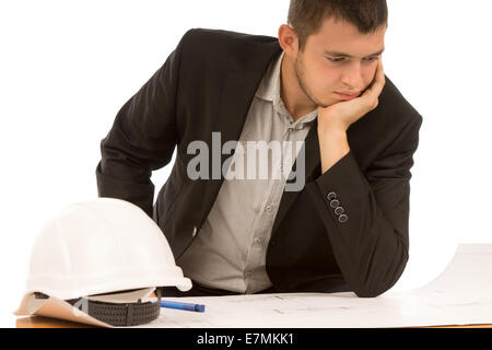 Young engineer, builder or architect sitting with his chin resting on his hand puzzling over a blueprint, on white Stock Photo