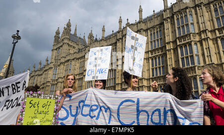 A group of demonstrators hold placards and a banner which says 'System Change' in front of the Houses of Parliament during the Climate Change demonstration, London, 21st September 2014. © Sue Cunningham Stock Photo