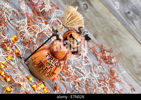 Horizontal angled image of a scary orange pumpkin figure holding straw broom placed on rustic wooden boards Stock Photo