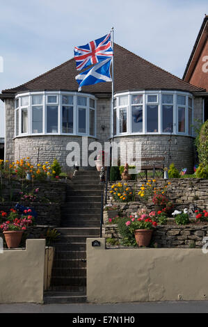 United Kingdom flags. The Union Jack and Scottish Saltire fly above a bungalow in England during the 2014 Scottish independence referendum campaign. Stock Photo