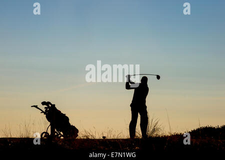 Golfer teeing off in the sunset Stock Photo