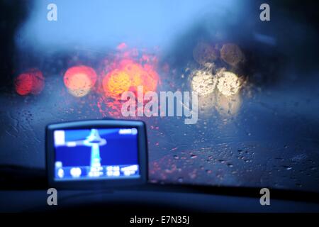 A satellite navigational (sat nav) fitted in a car driving at night in the rain. Stock Photo