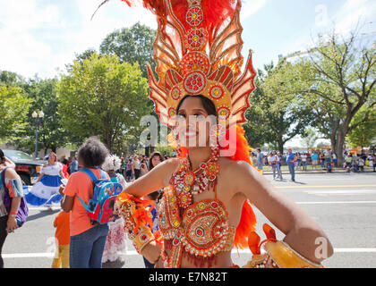 Woman in brazilian samba carnival costume with colorful feathers plumage  with mobile phone take selfie in old entrance with big window. Stock Photo