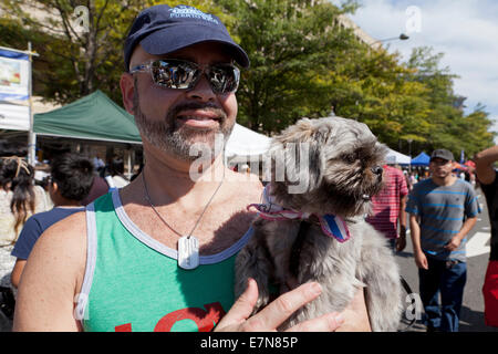 Man holding up a Pekingese dog in arms - USA Stock Photo
