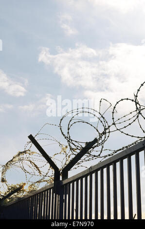 Galvanised high security razor wire and barbed wires deterrent to slow down climbing over walls with mass of shredded plastic Stock Photo