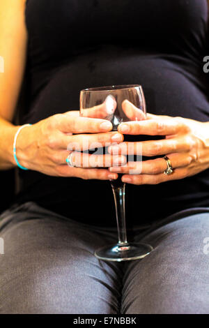 Pregnant woman holding a glass of wine Stock Photo