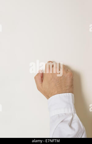 Male hand is knocking on wooden door, conceptual image. Visitor or guest is at the door. Stock Photo