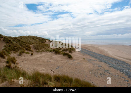 low down shot of beach with pebbles, grassy dunes and contrasting sky in Ynyslas, Wales, UK Stock Photo