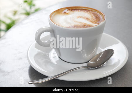 White cup of cappuccino stands on the table, selective focus Stock Photo