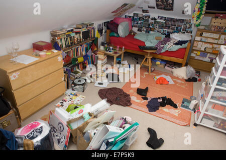 A teenager's messy bedroom with clothes, books and possessions ...