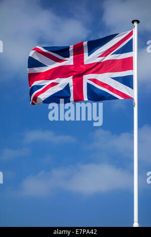 Union Jack / national flag of the United Kingdom on flagpole flying in the wind against cloudy sky Stock Photo