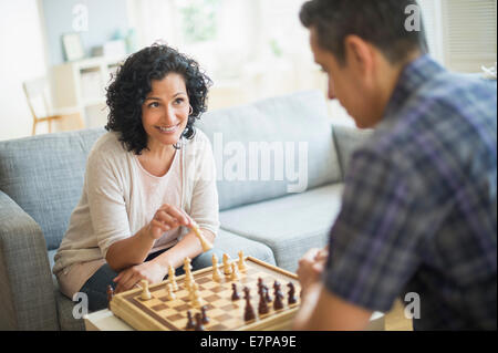 Couple playing chess in living room Stock Photo