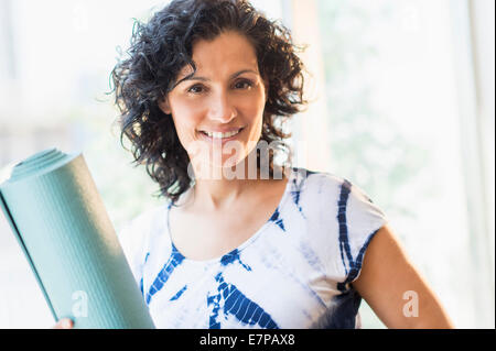 Portrait of smiling woman with yoga mat Stock Photo