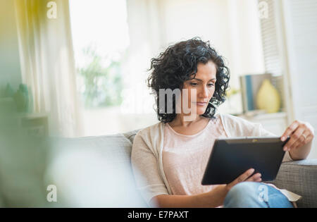 Woman using digital tablet on sofa Stock Photo
