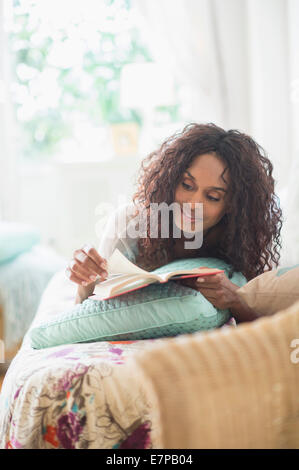 Woman reading book on bed Stock Photo