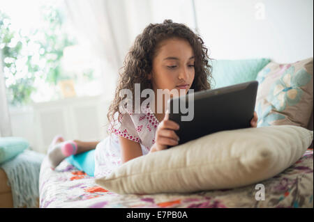 Girl (8-9) using digital tablet on bed Stock Photo