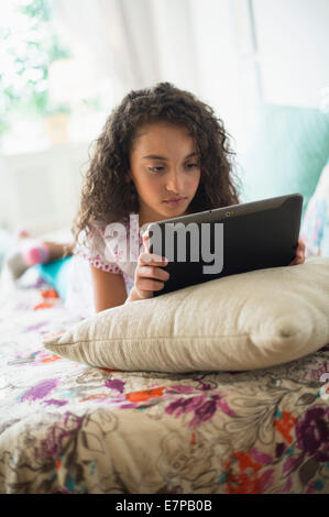 Girl (8-9) using digital tablet on bed Stock Photo