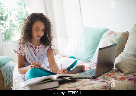 Girl (8-9) studying on bed Stock Photo