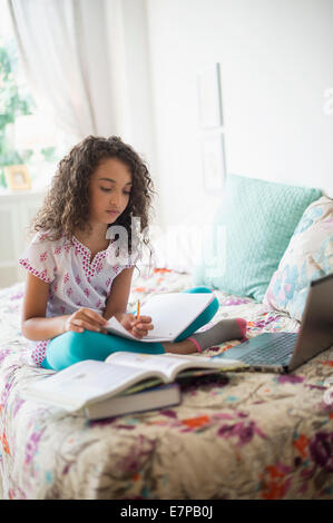 Girl (8-9) studying on bed Stock Photo