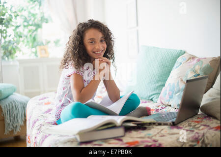 Girl (8-9) studying on bed Stock Photo