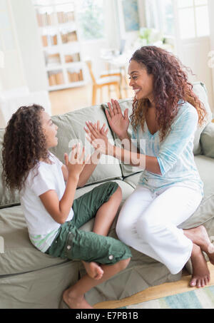 Daughter (8-9) and mother playing clapping game Stock Photo