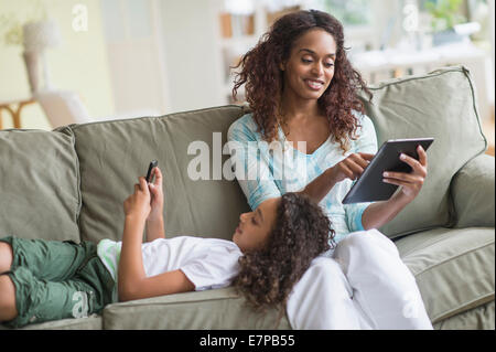 Mother and daughter (8-9) relaxing on sofa Stock Photo