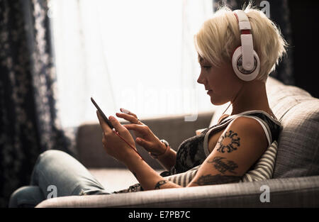 Woman sitting on sofa using digital tablet Stock Photo