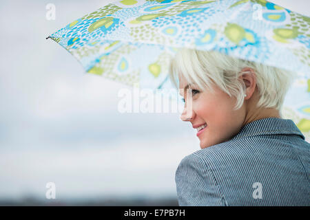 Profile of blonde woman under umbrella Stock Photo