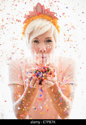 Woman wearing tiara blowing confetti Stock Photo