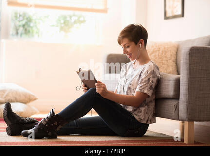Young woman sitting on floor and using tablet pc Stock Photo